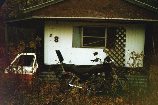 An abandoned trailer and motorcycle.
